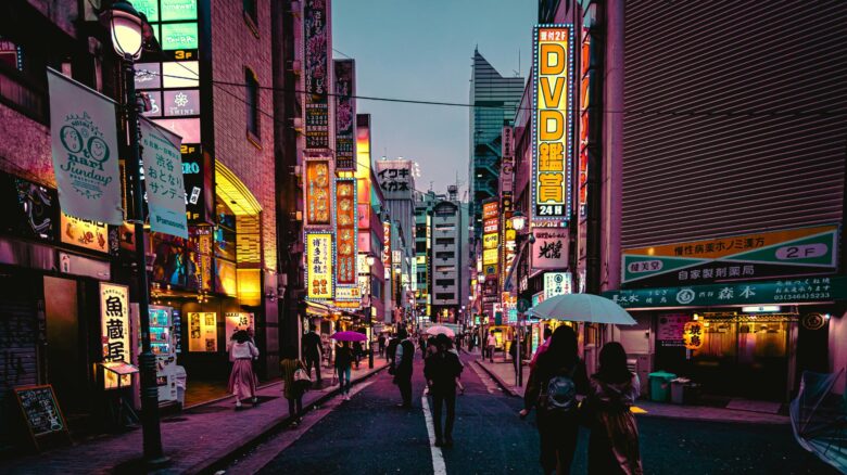 Neonowa ulica w Tokio wieczorem z japońskimi szyldami i przechodniami parasolkami